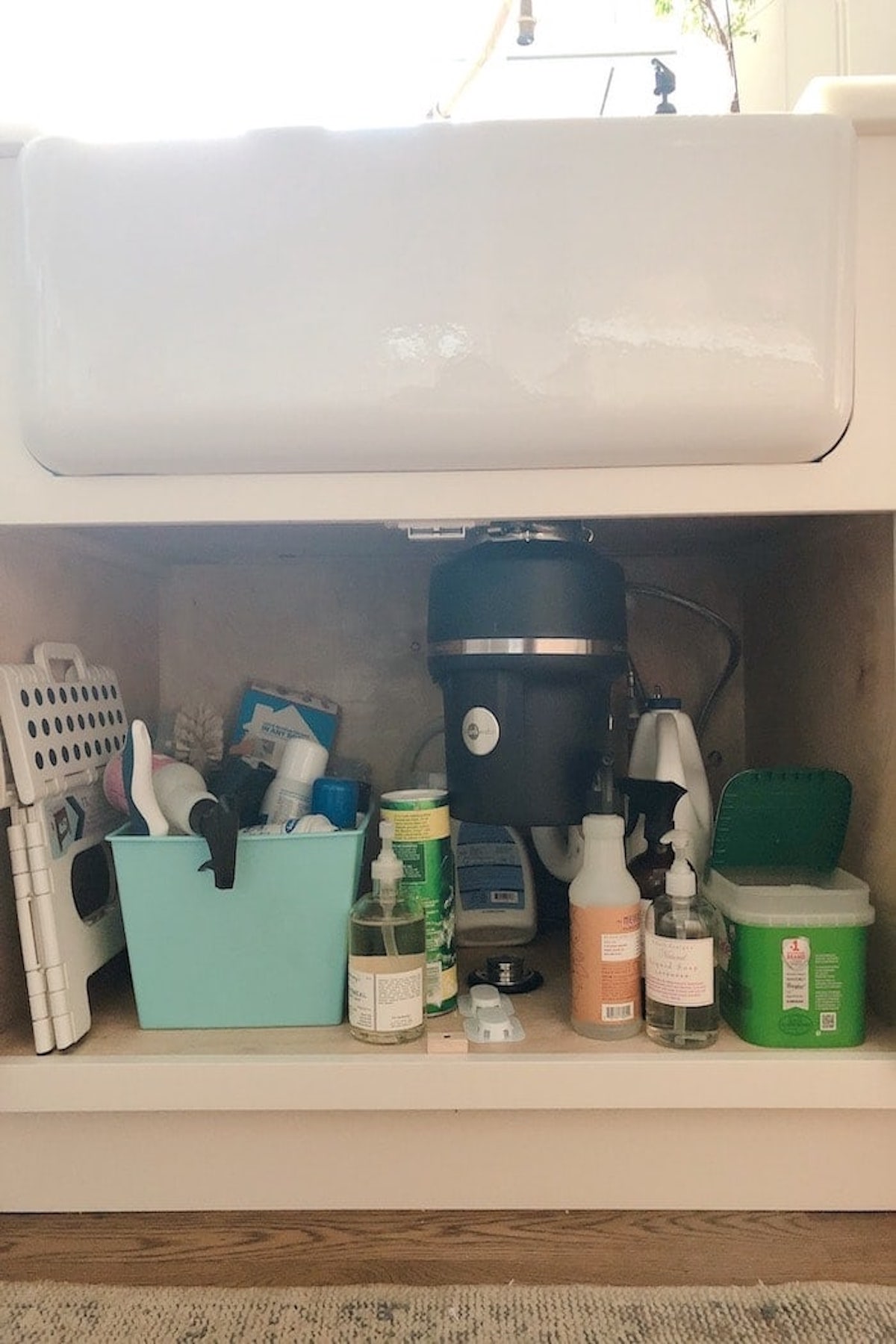 An assortment of cleaning supplies neatly placed under the kitchen sink for efficient under sink storage.