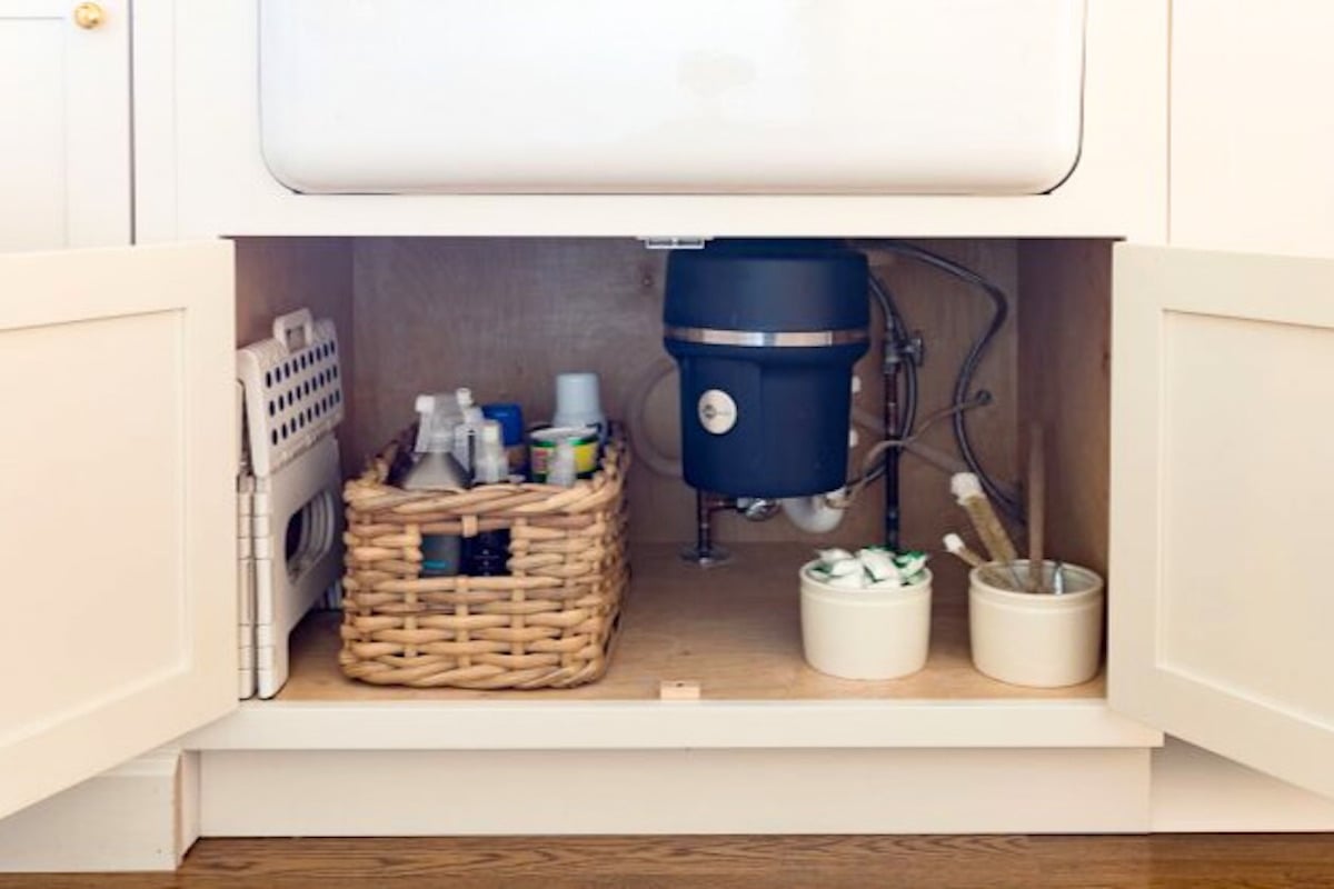 A white kitchen with UNDER SINK STORAGE and baskets under the sink.