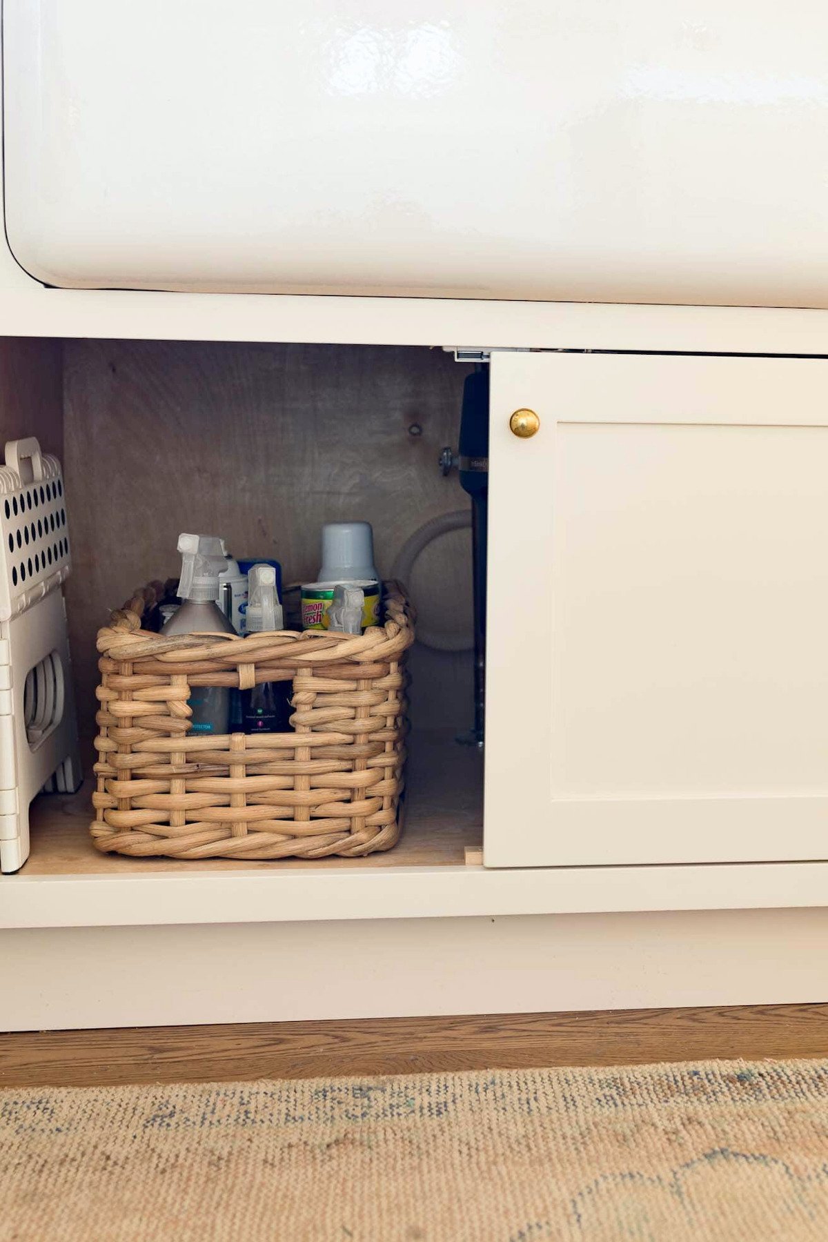 A laundry room with UNDER SINK STORAGE ideas, showcasing a basket beneath the sink.