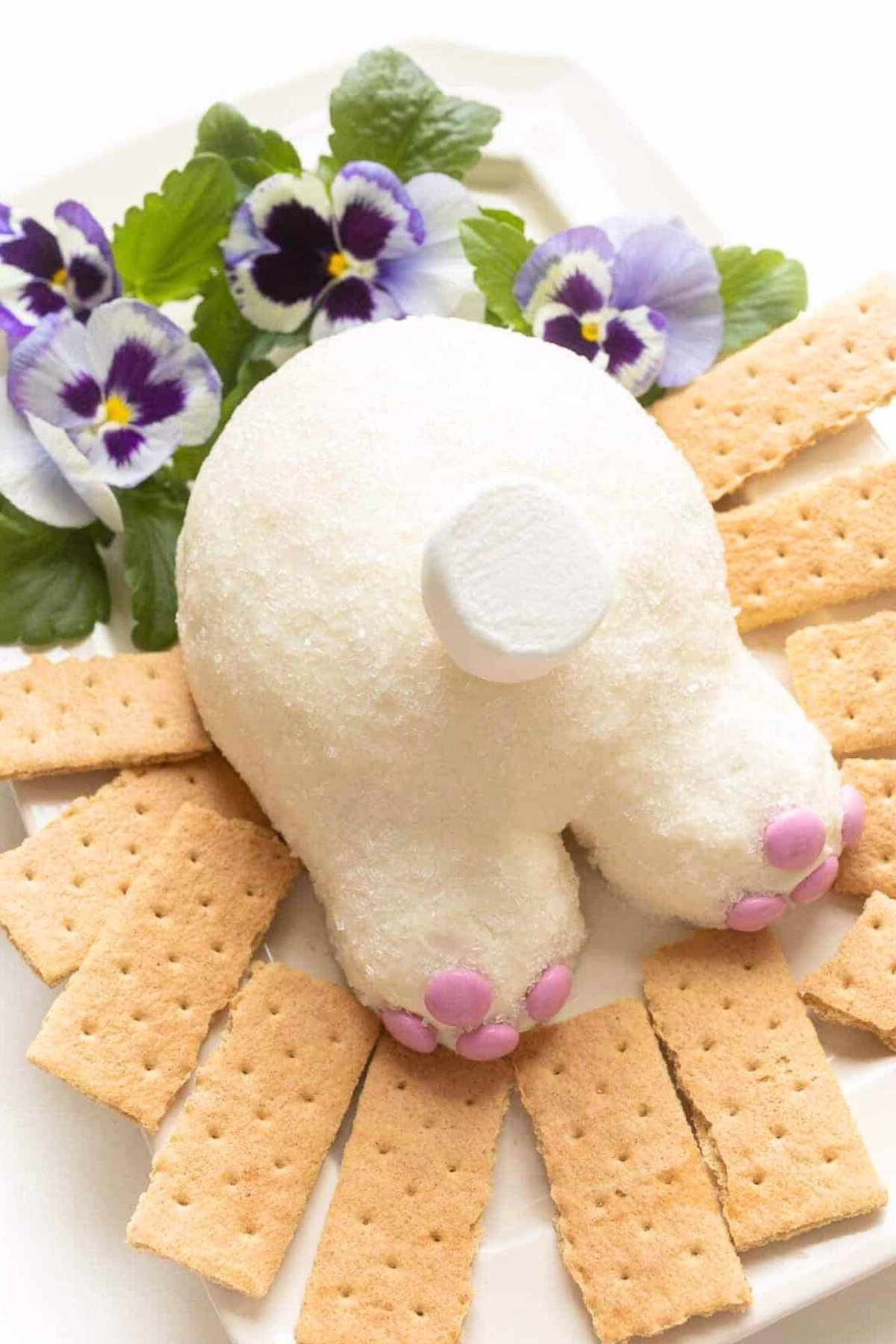 A bunny dessert cheeseball surrounded by fresh flowers and graham crackers