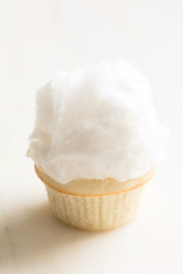 A cotton candy-topped ice cream cone against a plain background, resembling Easter cupcakes.