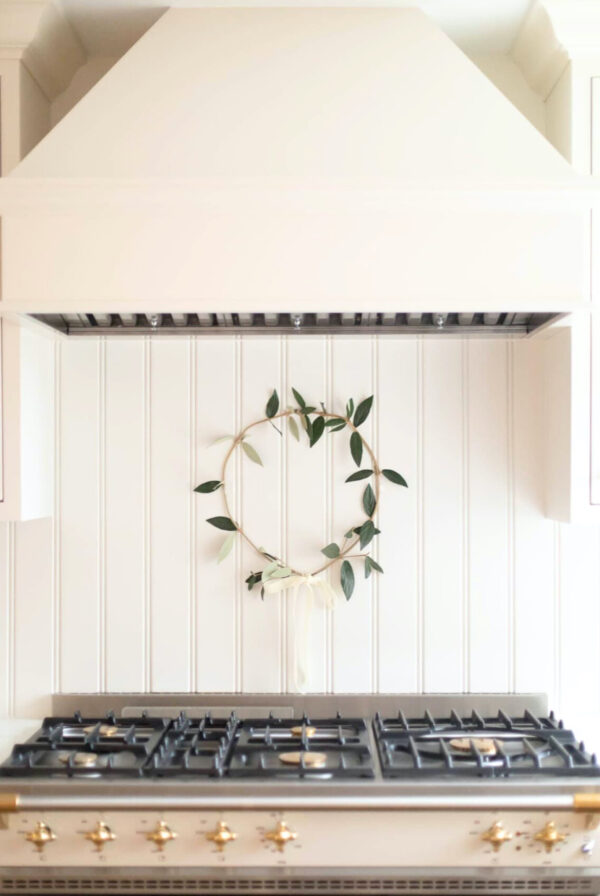 A cream kitchen with a simple greenery wreath hanging behind the range.