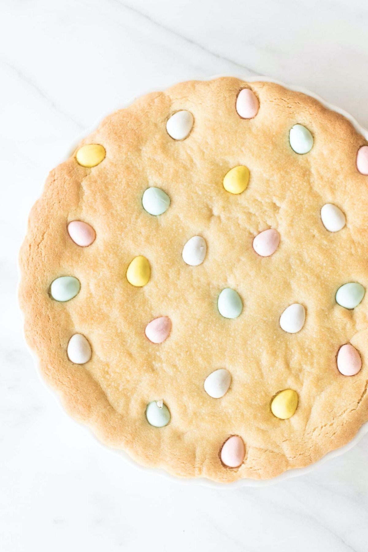 A freshly baked cookie cake with pastel-colored Cadbury Easter eggs embedded on top.