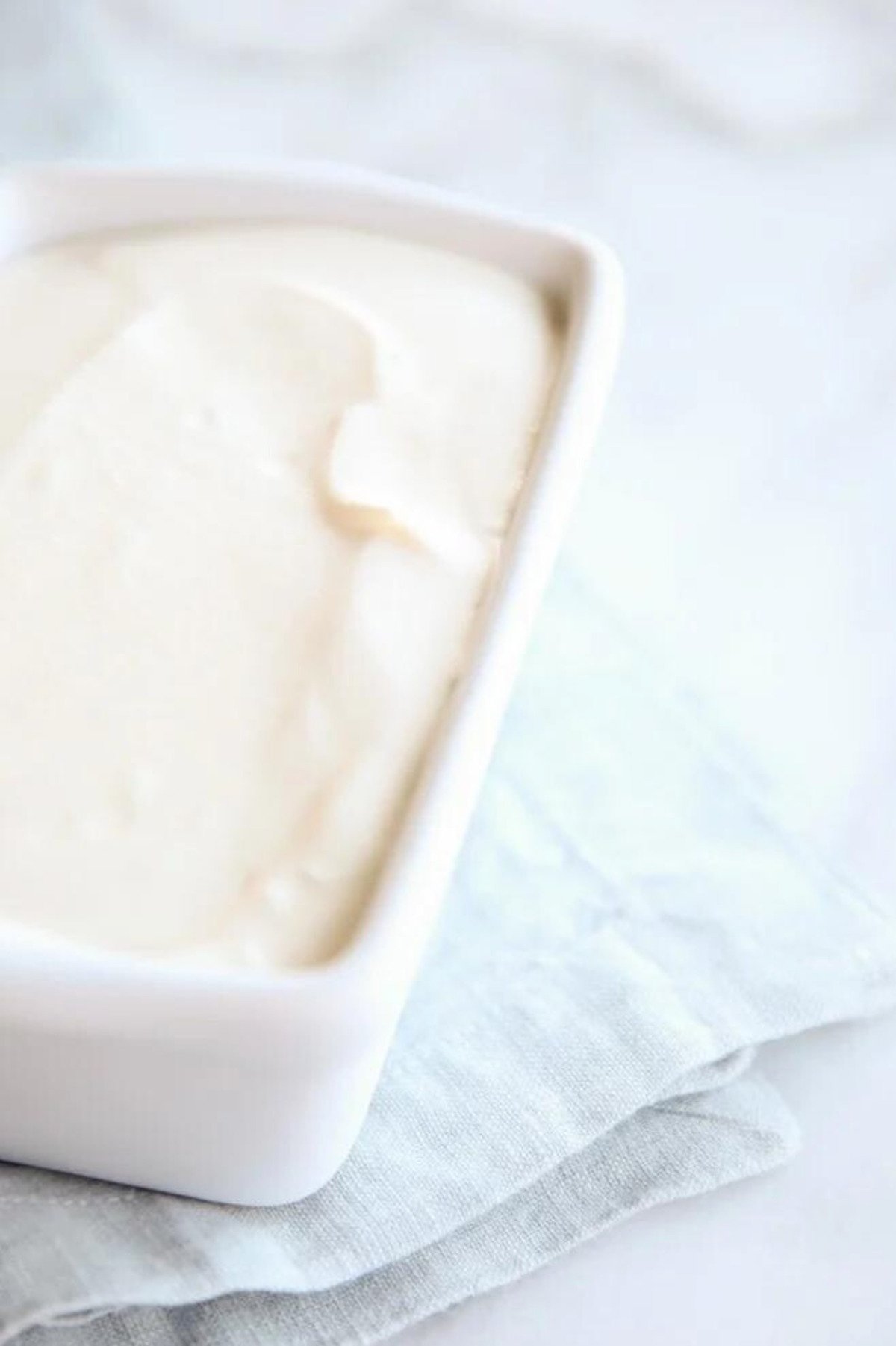 Homemade vanilla ice cream in a white dish on a napkin.