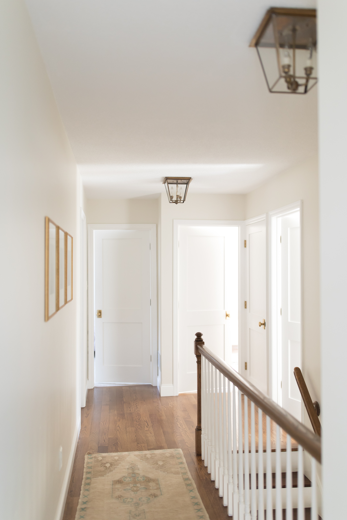 A hallway with white shaker doors and wood floors
