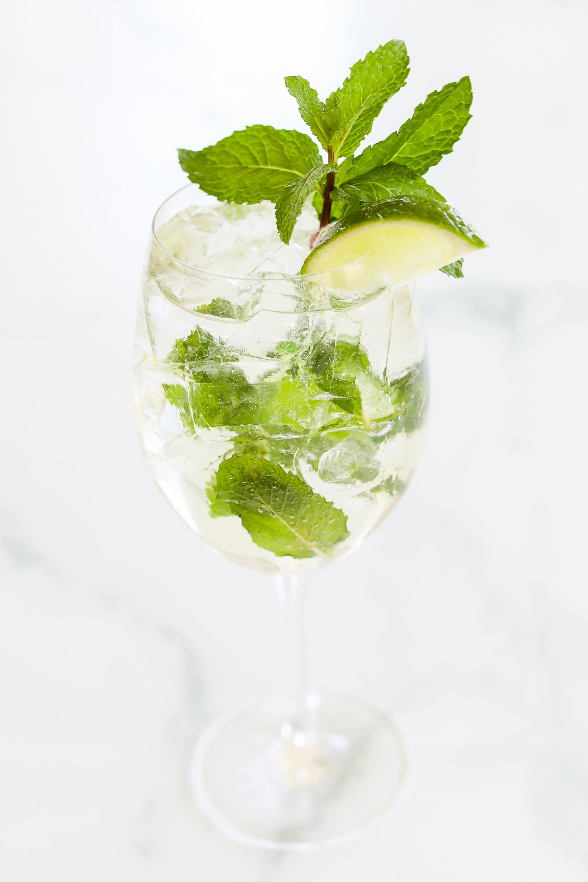 A refreshing Hugo spritz cocktail with lime and mint in a tall glass.