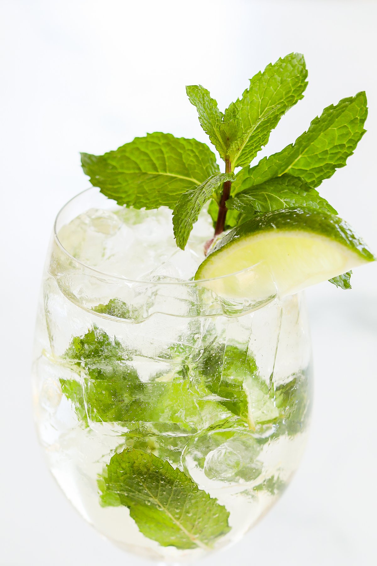 A glass of Hugo spritz garnished with fresh mint leaves and a slice of lime.