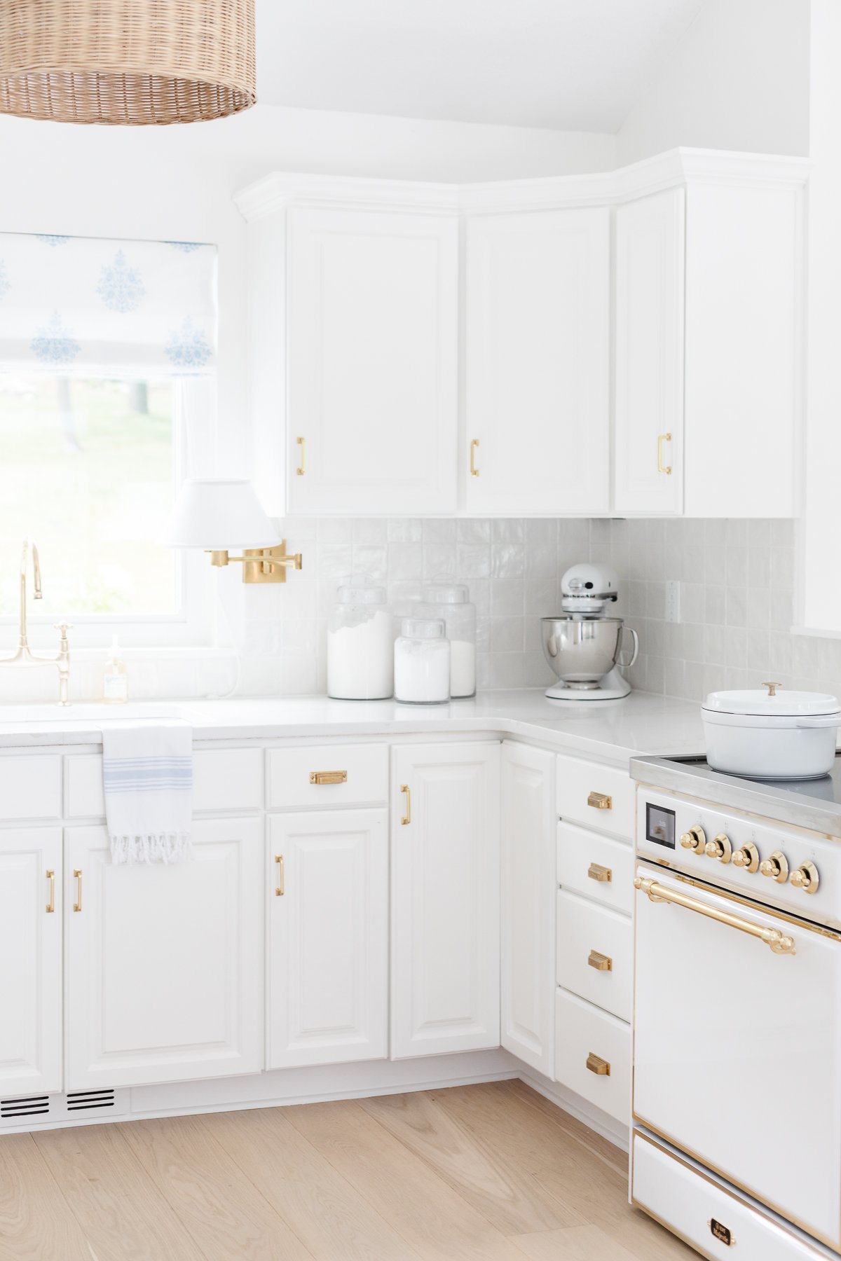 A bright, white modern kitchen with gold hardware, a classic stand mixer, and an Ilve range.