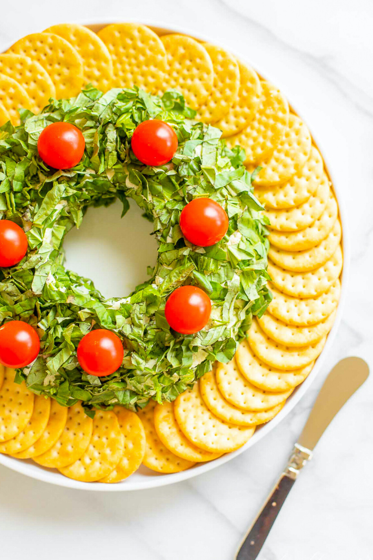 A plate with a wreath of crackers and tomatoes, perfect as Christmas appetizers.