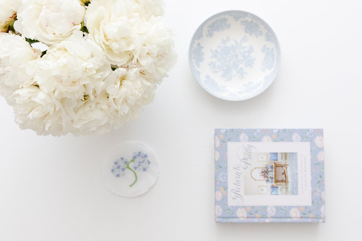 A white peony flower next to a book.