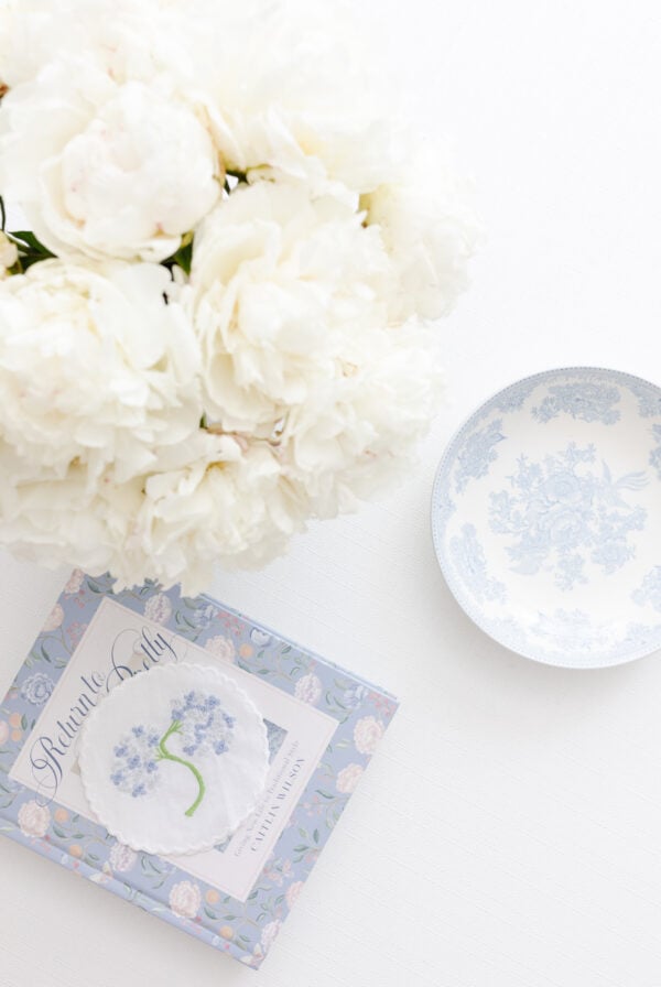 White peony flowers and a book on a table.