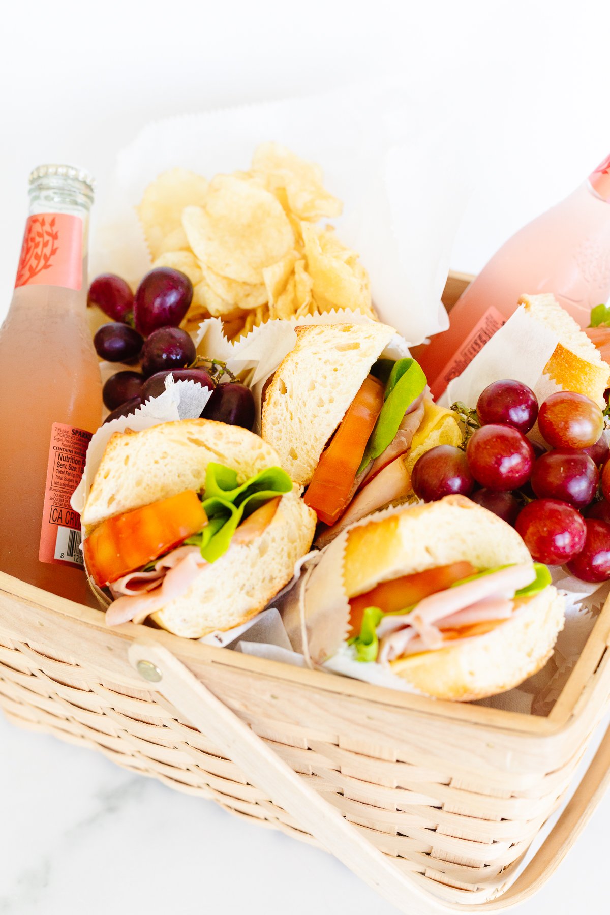 A wicker basket filled with Fourth of July picnic sandwiches and grapes.