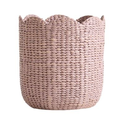 A woven basket with a light beige color and scalloped edge, perfect for adding charming scalloped decor to any space.