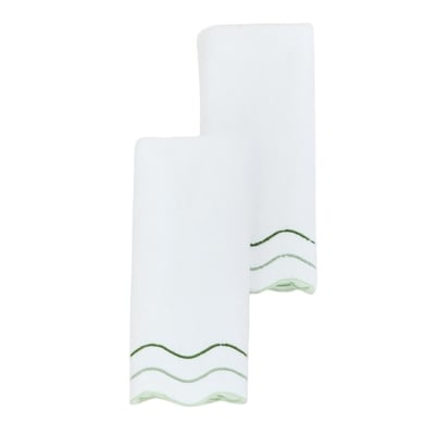 Two white napkins with scalloped green trim.