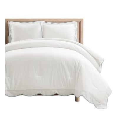 A white comforter set with scalloped blue trim.