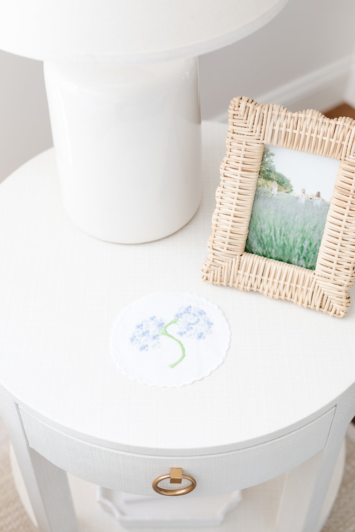 A white nightstand with scalloped decor and a picture of a flower on it.
