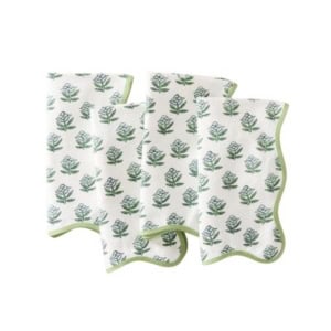 Four white cloth napkins with a green leafy pattern and scalloped decor trim are displayed overlapping on a white background.