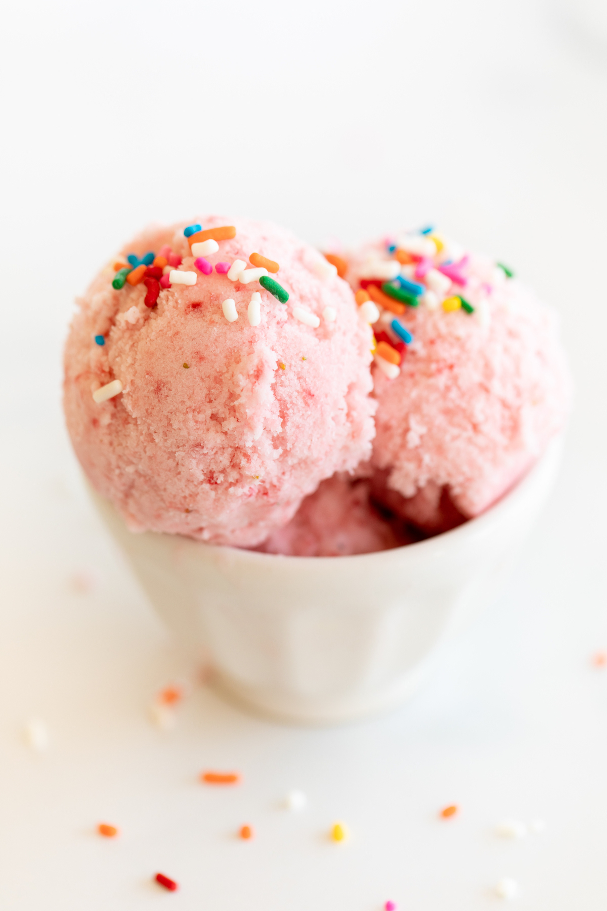Strawberry pink ice cream in a bowl with sprinkles.