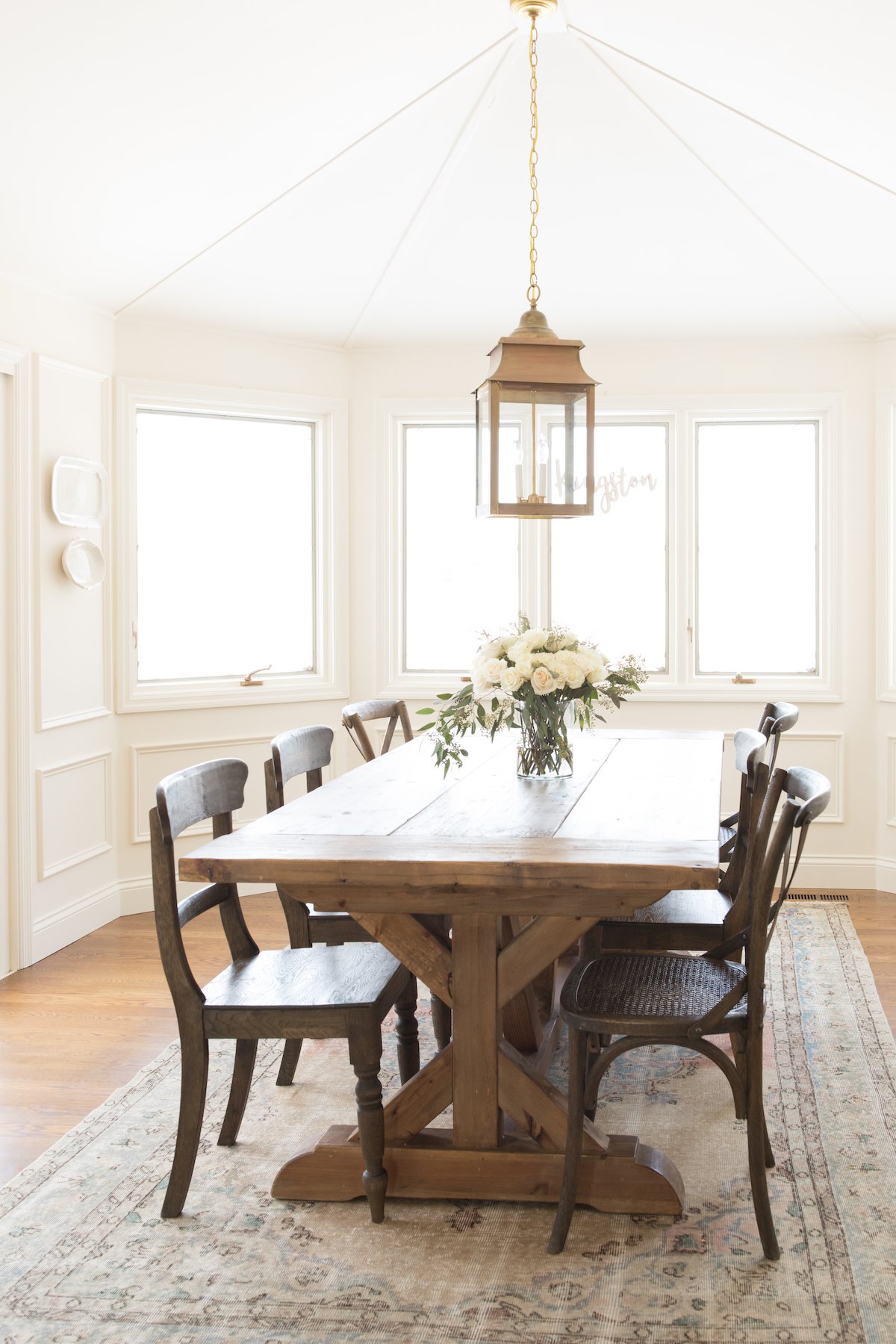 A dining room painted in Benjamin Moore Navajo White, with a wood farm table and an antique rug. 