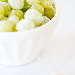 A bowl of Prosecco-coated grapes on a white surface.