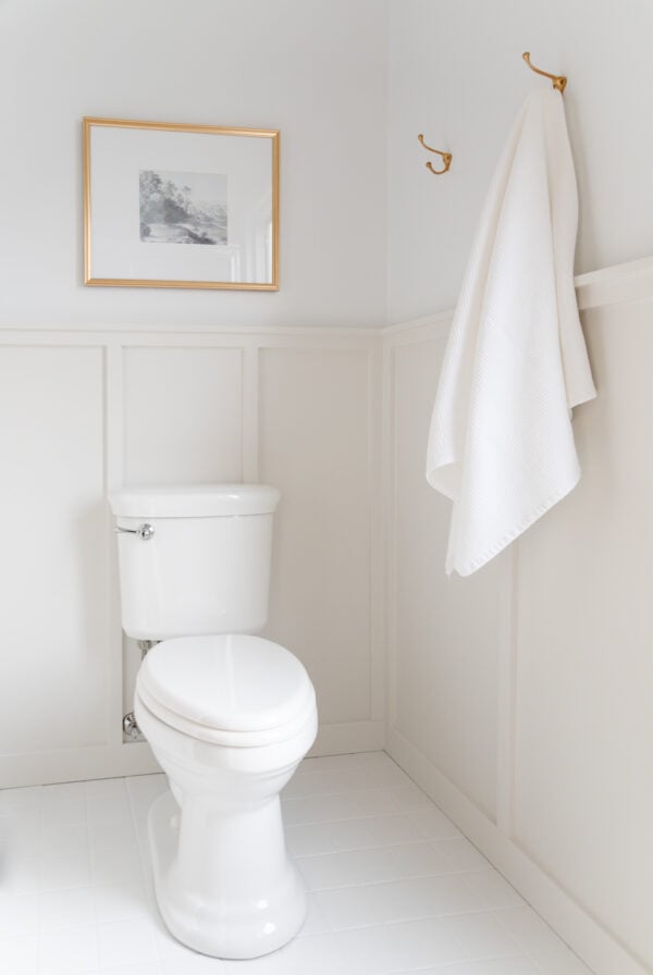 A small bathroom with white tile paint on the floors, and neutral board and batten on the walls.
