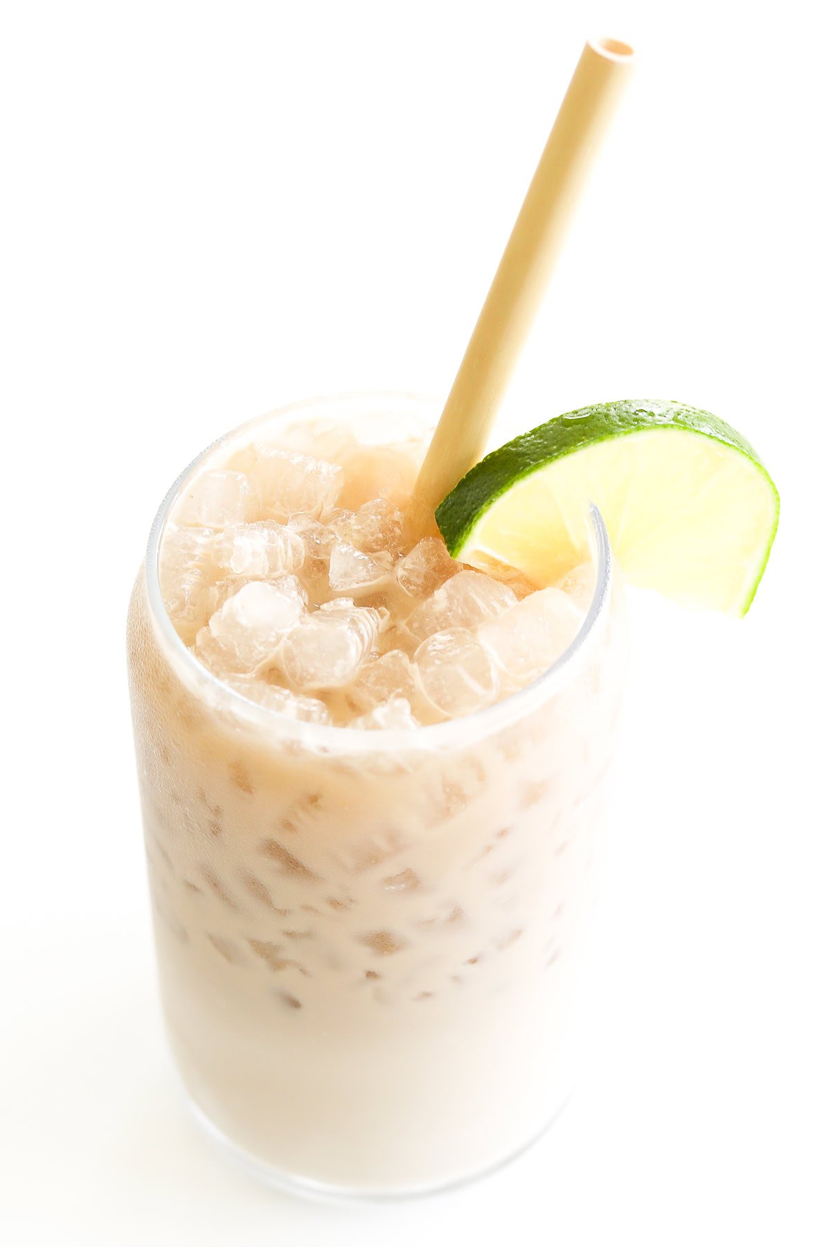 A close-up of an iced dirty Dr Pepper, garnished with a slice of lime on the rim, featuring a straw for sipping.