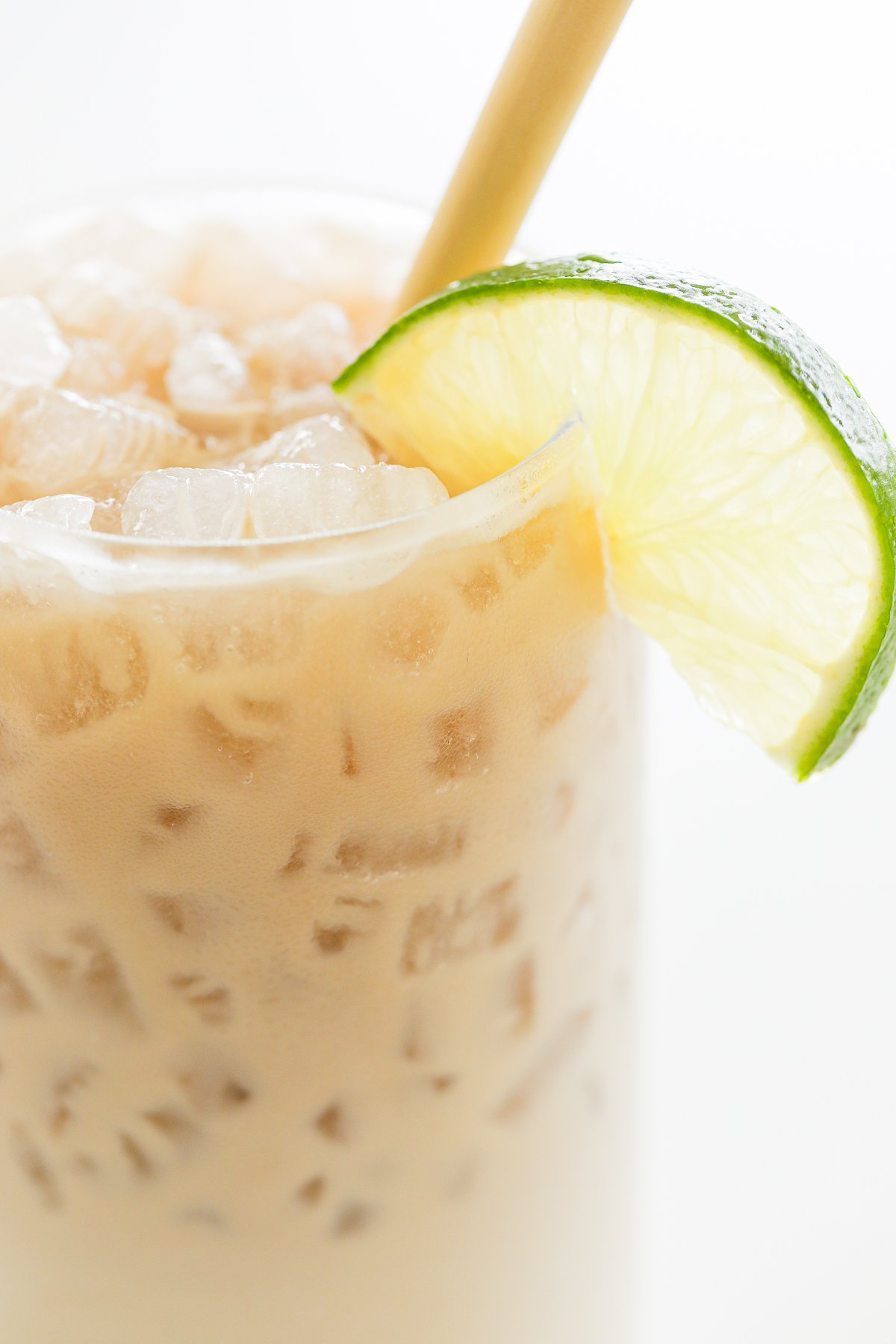 A close-up of an iced dirty Dr Pepper, garnished with a slice of lime on the rim, featuring a straw for sipping.