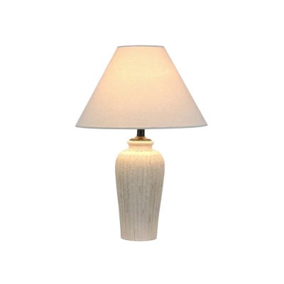 A table lamp with a beige, textured ceramic base and a simple off-white lampshade, offering a Pottery Barn look for less.