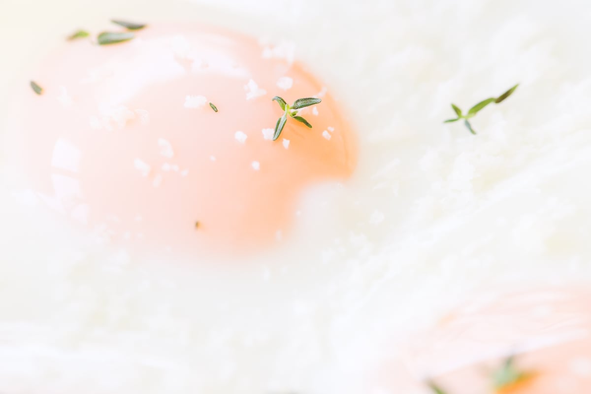 Close-up view of Sheet Pan Eggs sprinkled with salt, pepper, and fresh thyme leaves.