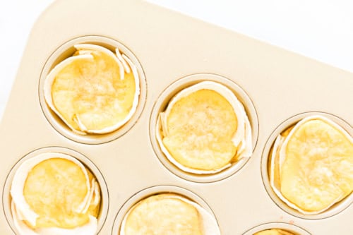 A close-up of six round Mexican Breakfast Cups in a muffin tin, with a golden-brown, smooth surface on top.