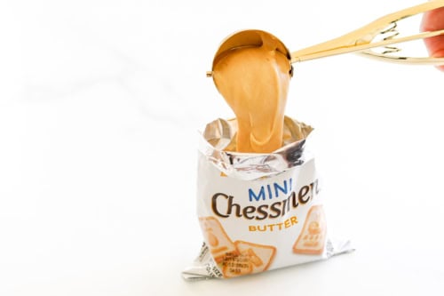 Peanut butter being scooped into an open pack of Mini Chessmen Butter cookies.