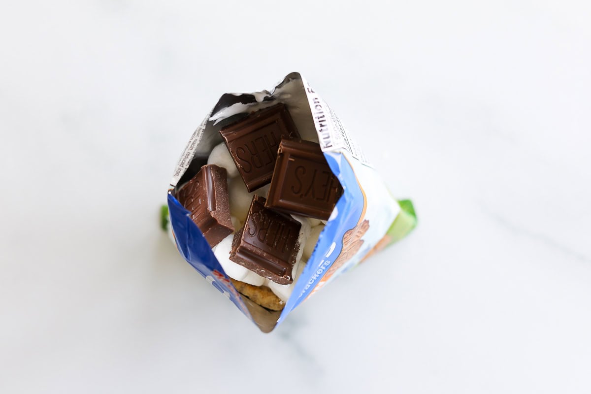 An open bag of graham crackers with chocolate and marshmallows inside for walking smores.