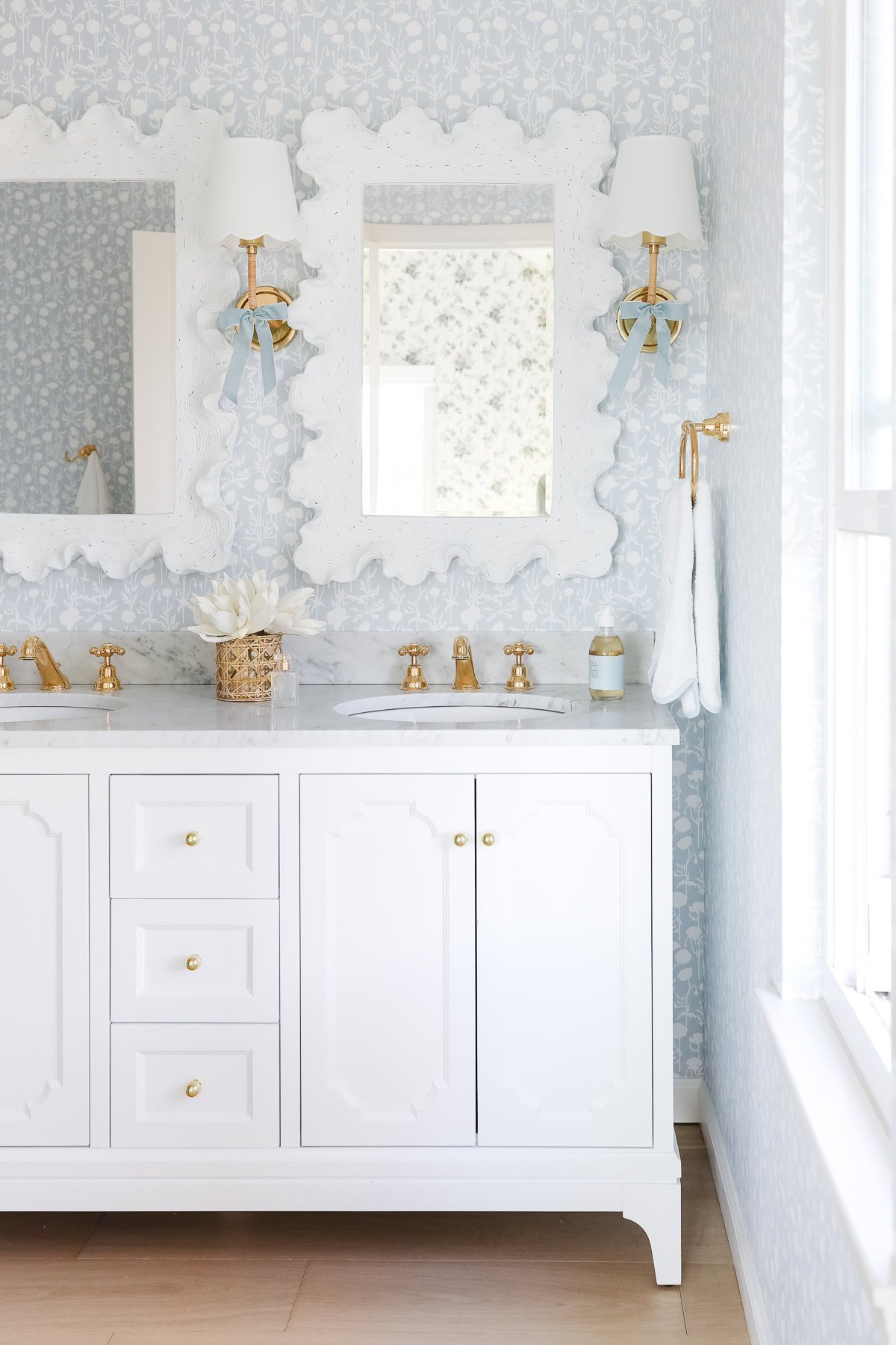 Elegant bathroom showcasing a white vanity with gold fixtures, decorative mirrors, and patterned wallpaper—perfect for a Prime Day refresh.