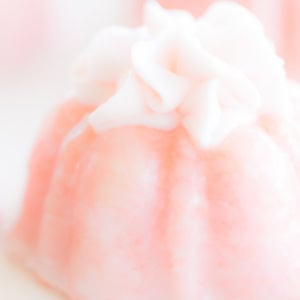 Close-up of a decorative pink gelatin dessert crowned with fluffy white whipped cream and a hint of champagne frosting.