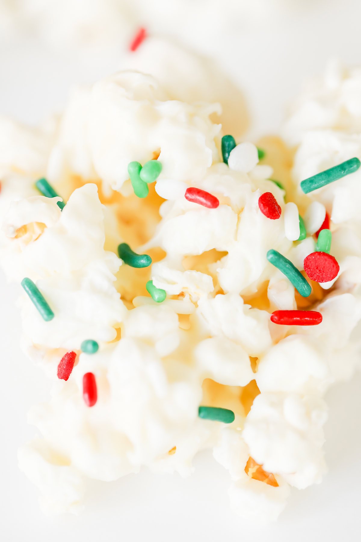 Close-up of Birthday Cake Popcorn topped with a white coating and festive red, green, and white sprinkles.