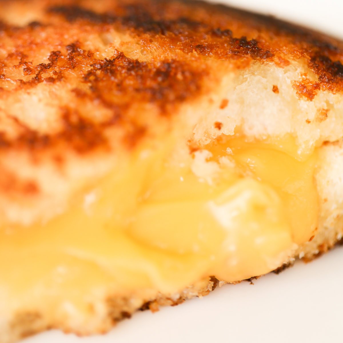 Close-up of a golden-brown campfire grilled cheese sandwich with melted cheese oozing from the center.