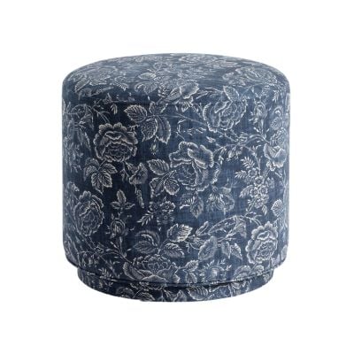 A round, blue ottoman with a white floral pattern covering its surface, offering a chic Pottery Barn look for less.