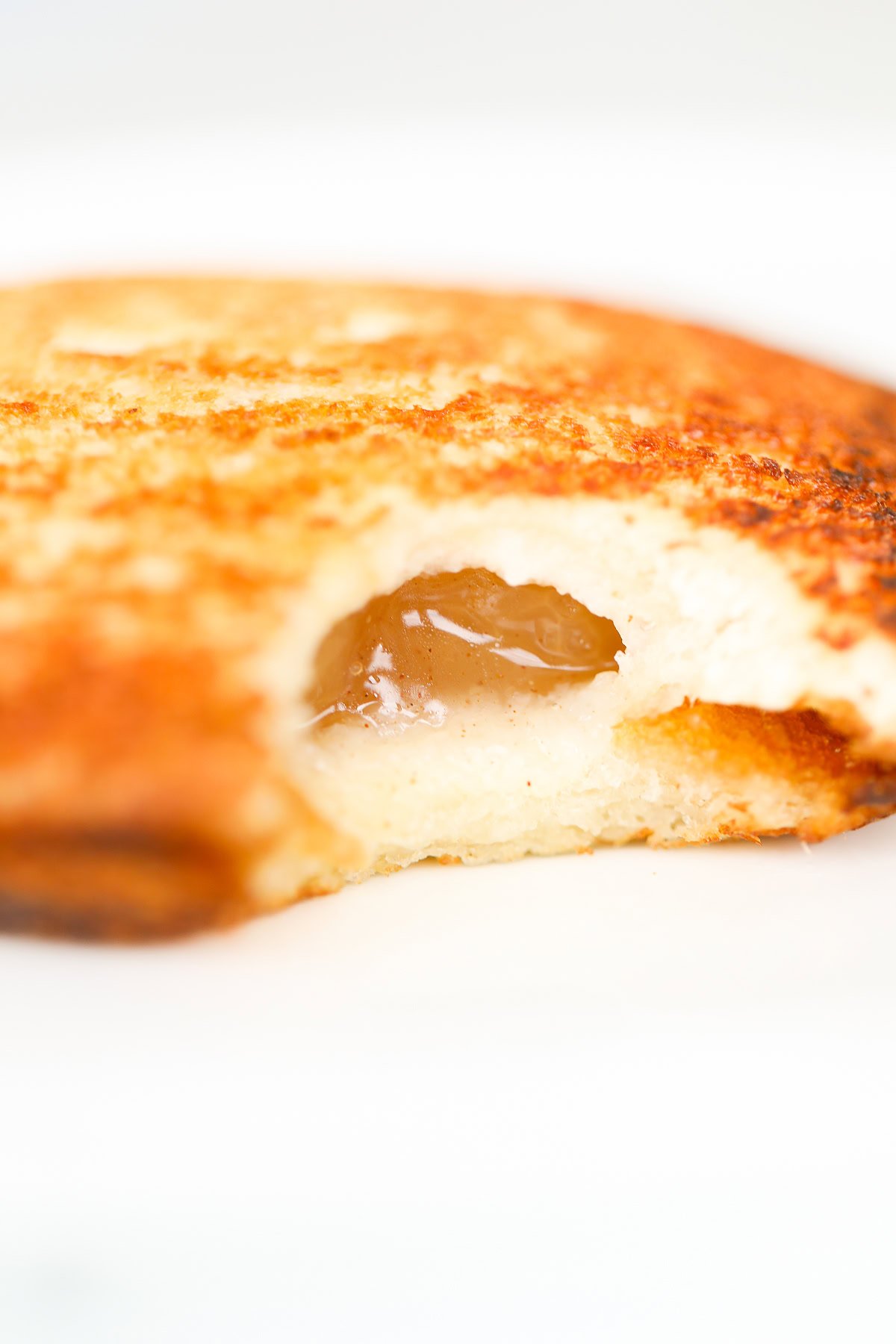 Close-up of a pudgy pie with a bite taken out, revealing a luscious jam filling inside.