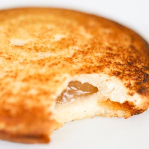 Close-up of a pudgy pie with apple filling visible inside, on a plain white background.