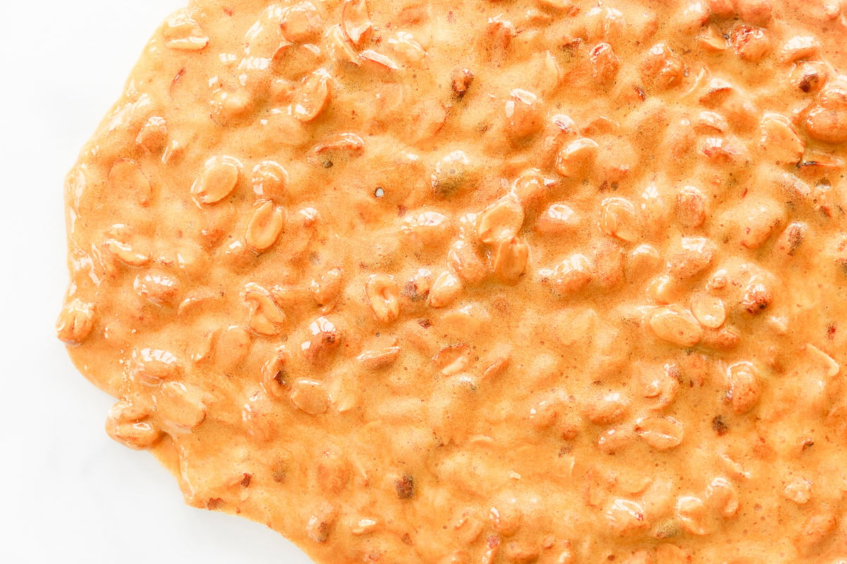 Close-up of a spread of textured orange and brown peanut butter, reminiscent of the crunchy, caramelized finish found in classic peanut brittle.