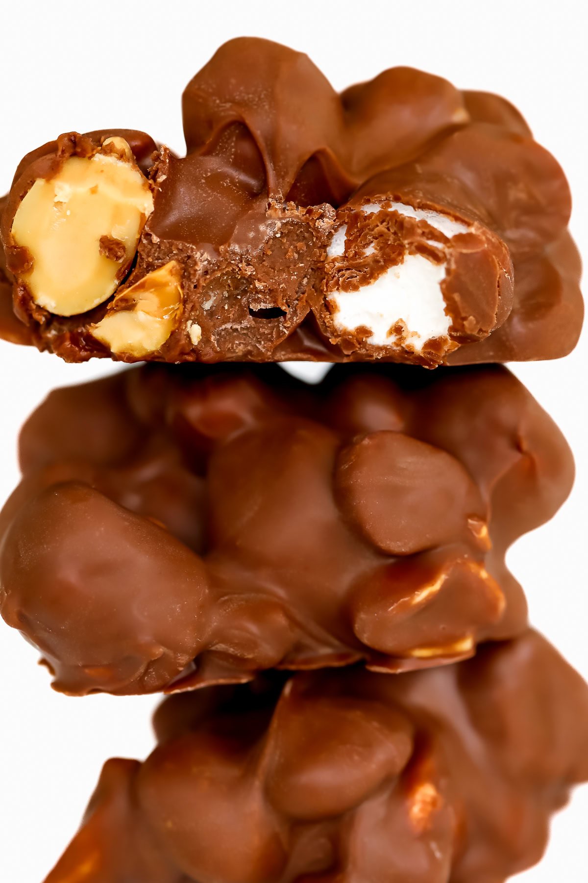 Close-up of stacked Rocky Road Candy clusters, with nuts and marshmallow pieces elegantly peeking through the top one.