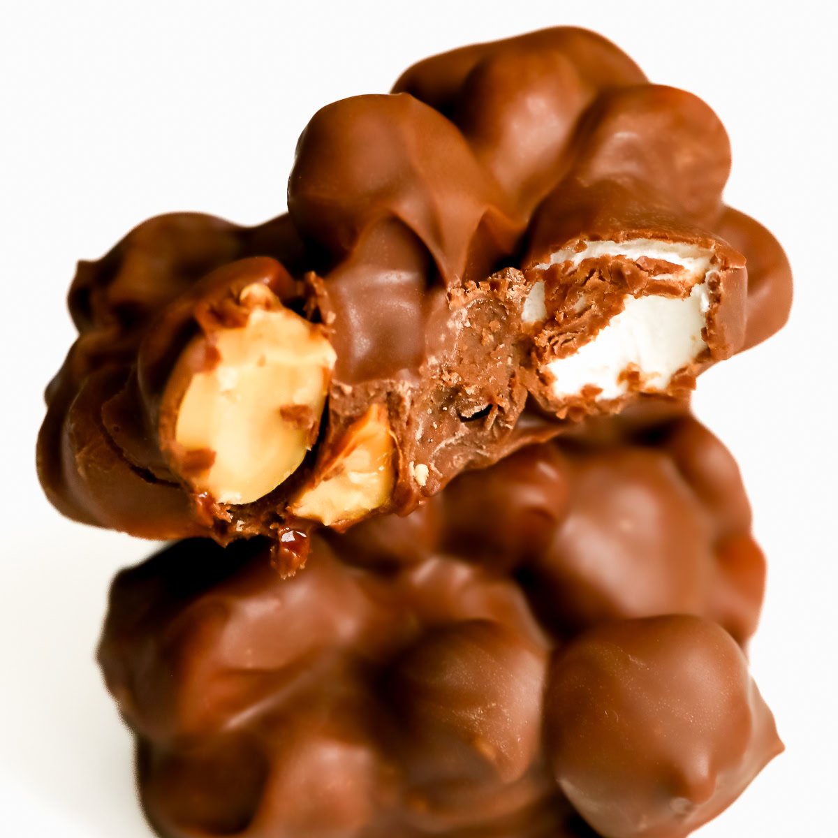 Close-up of Rocky Road Candy clusters with visible nuts and a marshmallow center against a plain white background.