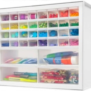 A white storage organizer with multiple compartments neatly holds colorful office supplies like paper clips, push pins, and adhesives, making it perfect for organizing crafts.