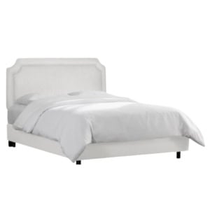 A white upholstered bed with a rectangular headboard and crisp white bedding offers a serene, Serena and Lily look for less, set against a plain background.