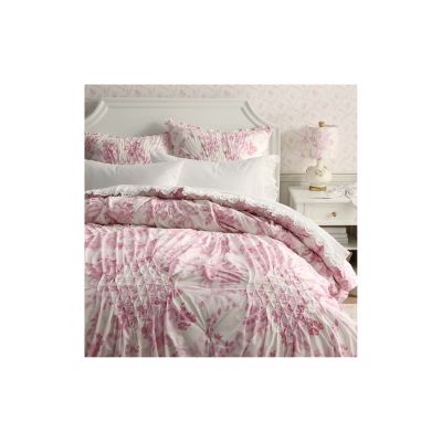 This bedroom captures the LoveShackFancy look for less with a white bed, pink floral bedding, matching pillows, and a coordinated floral lampshade on the bedside table.