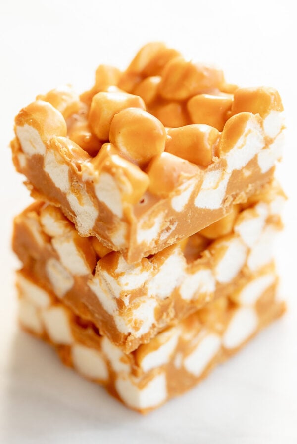 Three stacked squares of butterscotch and peanut butter marshmallow bars on a white background.