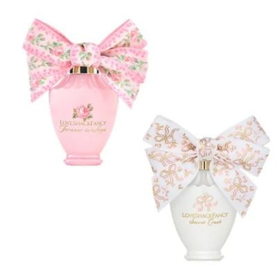 Two perfume bottles with large decorative bows—ideal Easter basket fillers. One is pink with a floral pink bow, the other white with a floral white bow. Both feature elegant gold text on the front.