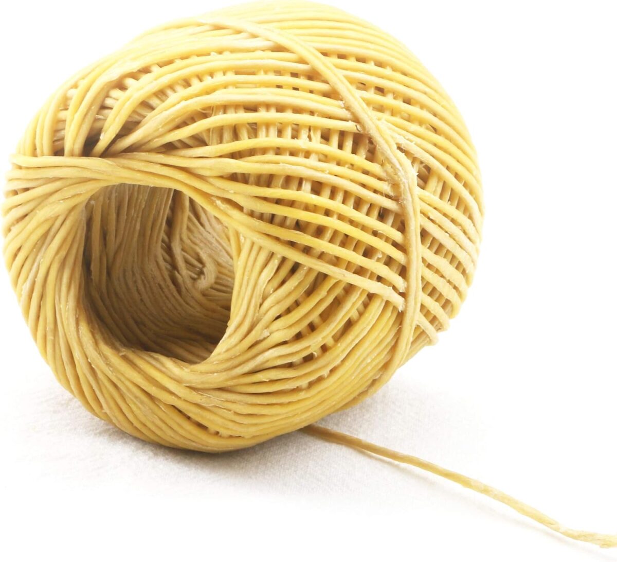 A ball of beige twine rests on a white surface, with one loose end extending outward.