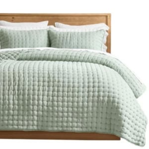 Light green quilted bedding set with two matching pillows on a wooden bed frame, shown neatly made with a textured pattern—a perfect way to achieve the Serena and Lily look for less.