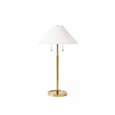 A brass table lamp with a round base, straight stem, white conical lampshade, and two pull chains offers a chic serena and lily look for less.
